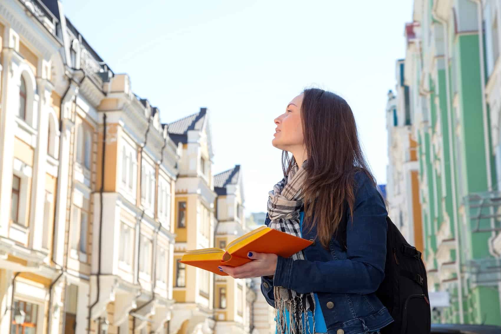 Travel. Young woman traveler with a backpack on her shoulder. Independent travel and out sightseeing in a history city. Student woman, her vacation. Learning foreign languages in a different country.